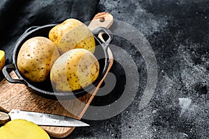 Recipe for fried potatoes, organic yellow potatoes in a pan. Black background. Top view. Copy space