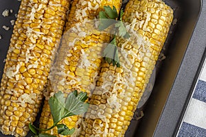 Recipe homemade cooking. Mexican Elote Corn sprinkled with cheese or parmesan and cilantro on baking sheet. Close up