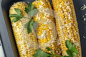 Recipe homemade cooking. Mexican Elote Corn sprinkled with cheese or parmesan and cilantro on baking sheet. Close up