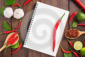 Recipe notebook, Red chilli, garlic and lemon on wooden backgro