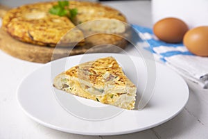 Spanish potato omelette with zucchini and young garlic. Traditional tapa recipe with egg, potato and onion. photo