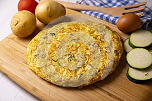 Spanish potato omelette with zucchini and young garlic. Traditional tapa recipe with egg, potato and onion. photo