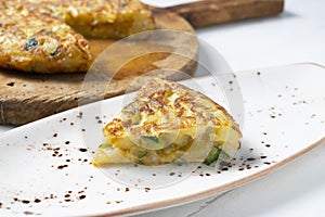 Spanish potato omelette with zucchini and young garlic. Traditional tapa recipe with egg, potato and onion. photo