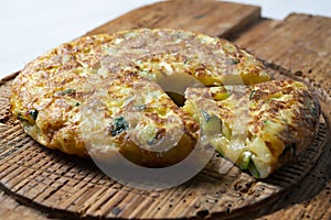 Spanish potato omelette with zucchini and young garlic. Traditional tapa recipe with egg, potato and onion. photo