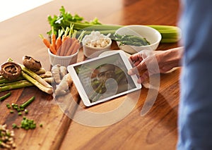 Recipes go paperless. Cropped shot of a man using a digital tablet while preparing a healthy meal at home.