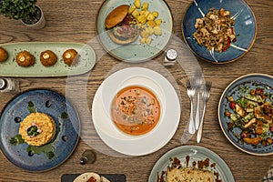 Recipes of modern Spanish dishes and tapas with boletus croquettes, salmorejo on a white plate, Russian salad and chicken and rice