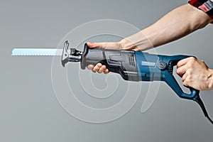 Reciprocating saw used in construction and demolition work, in male hands