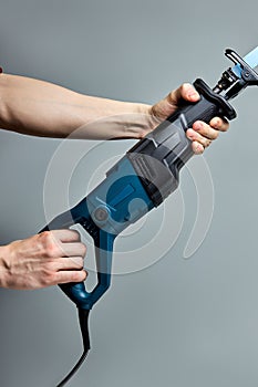 Reciprocating saw used in construction and demolition work, in male hands