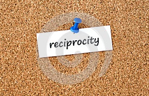 Reciprocity. Word written on a piece of paper, cork board background photo