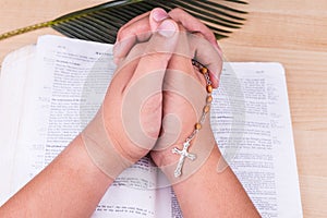 Reciting prayers using Catholic rosary with crucifix and bible