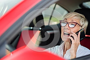 Reckless mature woman talking on the phone while driving a car