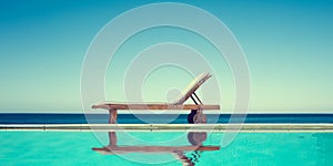 Reclining chair near a swimming pool, sea and blue sky