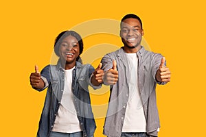We Recommend. Portrait of cheerful african couple gesturing thumbs up at camera