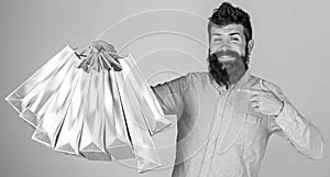 Recommendation concept. Guy shopping and pointing at bags. Man with beard and mustache carries bunch of shopping bags