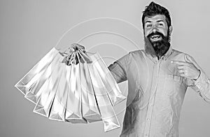 Recommendation concept. Guy shopping on sales season, pointing at bags. Hipster on smiling face recommends to buy. Man