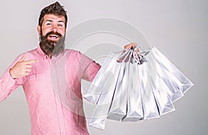 Recommendation concept. Guy shopping on sales season, pointing at bags. Hipster on smiling face recommends to buy. Man