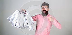 Recommendation concept. Hipster on happy face recommends to buy. Guy shopping and pointing at bags. Man with beard and