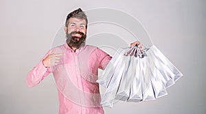 Recommendation concept. Hipster on smiling face recommends to buy. Guy shopping on sales season, pointing at bags. Man