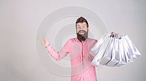 Recommendation concept. Hipster on smiling face recommends to buy. Man with beard and mustache carries bunch of shopping