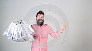 Recommendation concept. Hipster on smiling face recommends to buy. Man with beard and mustache carries bunch of shopping