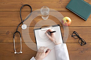 Recommendations and prescription from doctor. Woman in white coat writes on tablet at workplace