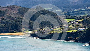 Recondite beaches in the north of Spain, with houses in the green fields next to the mountains, Lastres, Asturias.