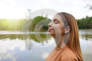 Reconnect with nature. Side view of young woman with closed eyes enjoying breathing in tropical park of Brazil