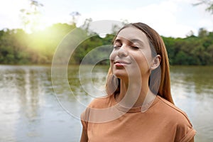 Reconnect with nature. Young woman with closed eyes enjoying breathing in tropical park of Brazil