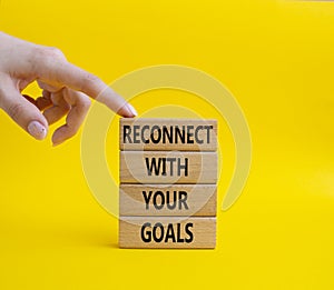 Reconnect with your Goals symbol. Wooden blocks with words Reconnect with your goals. Beautiful yellow background. Businessman