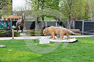 Reconstructed models of a Saber-toothed tiger and dino. The park of dinosaurs in Palas Public Garden in Iasi near Palatul culturii
