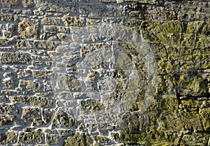 Reconstruction of a stone wall. the repaired part with the moss removed can be seen. blasted wall with pressurized water and fille