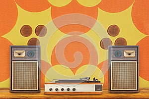 Record player with two vintage stereo speakers in front of retro seventies flower wallpaper