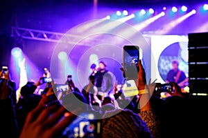 Recording a concert with mobile phone, silhouette of hands with smartphone