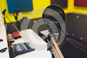 Recording equipment in studio. Studio microphone with headphones and mixer background. Elevated view.