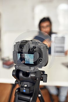 Recording video blog. Young man teaching online, explaining new theme while working from home. Focus on camera photo