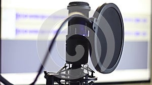 Recording Vocals with a Professional Studio Microphone Against the Background of a Sound Wave on a Computer Monitor Medium Shot