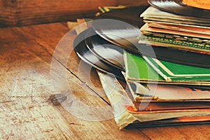 Records stack with record on top over wooden table. vintage filtered