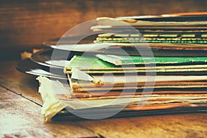 Records stack with record on top over wooden table. vintage filtered