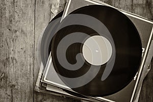 Records stack with record on top over wooden table. vintage filtered