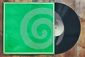 Records stack with record on top over wooden table. vintage filtered