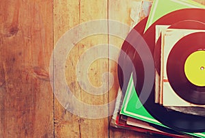 Records stack with record on top over wooden table. vintage filtered