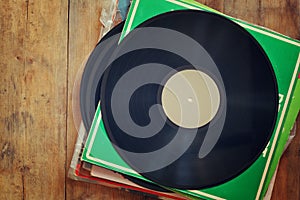 Records stack with record on top over wooden table. vintage filtered