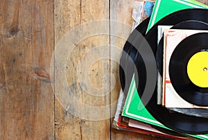 Records stack with record on top over wooden table. vintage filtered