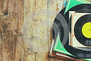 Records stack with record on top over wooden table. vintage filtered