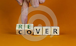 Recover symbol. Concept word `recover` on wooden cubes on a beautiful orange table. Businessman hand. Orange background. Busines