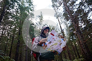 Recover your sense direction. a man in a pine forest with a map, figuring out his orientation.