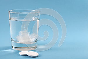 Recovering from a hangover and nursing a headache with aspirin concept with effervescent drink tablet dissolving in water with two