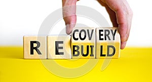 Recovery and rebuild symbol. Businessman turns cubes and changes the word `recovery` to `rebuild`. Beautiful yellow table, whi
