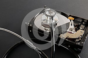 RECOVERY AND REPAIR TECHNOLOGY CONCEPT: Hard Disk Drive HDD with stethoscope isolated on a black background.