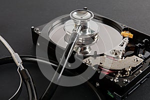 RECOVERY AND REPAIR TECHNOLOGY CONCEPT: Hard Disk Drive HDD with stethoscope isolated on a black background.